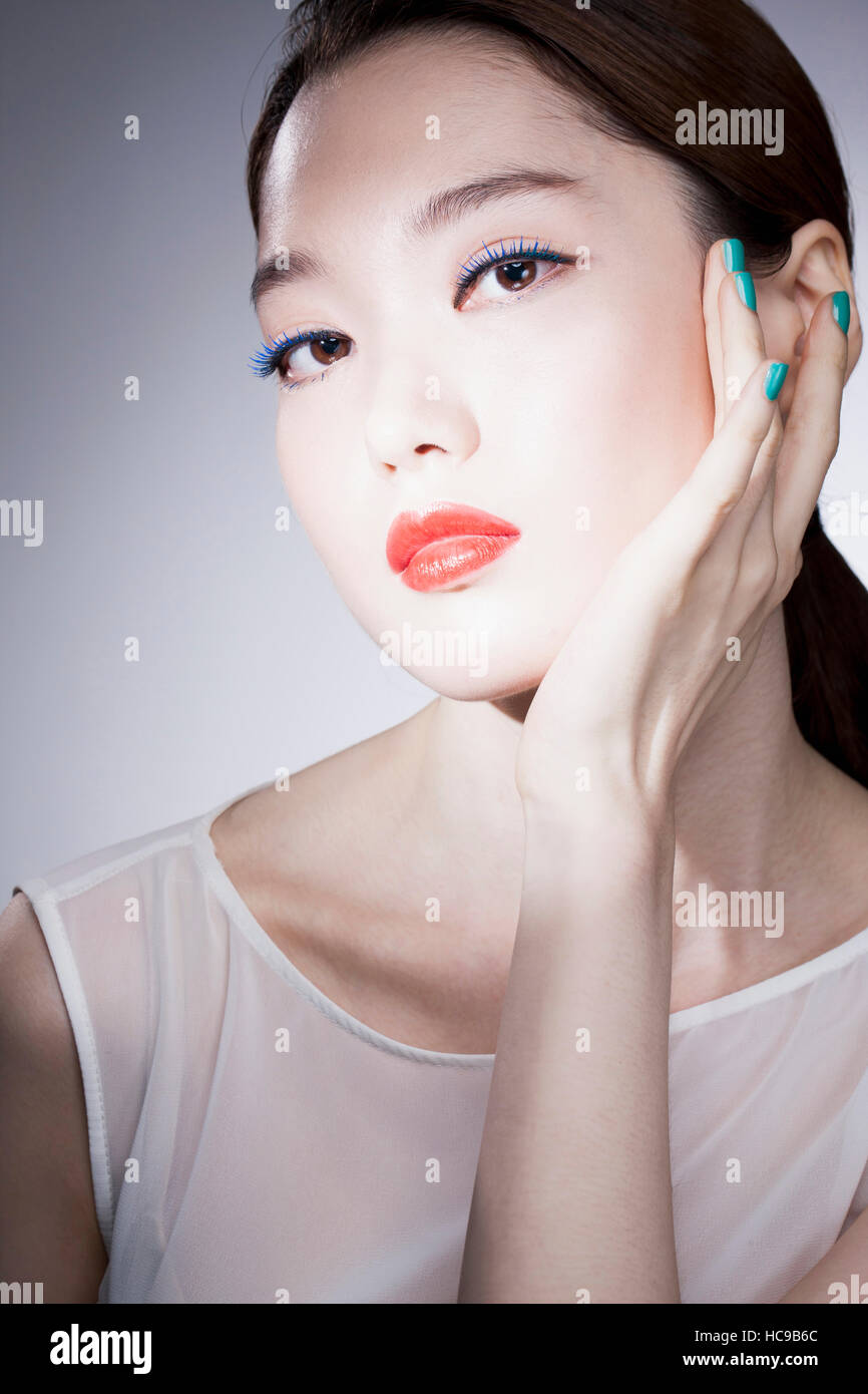 Portrait de jeune femme coréenne posant avec des clous bleu et rouge lèvres Banque D'Images