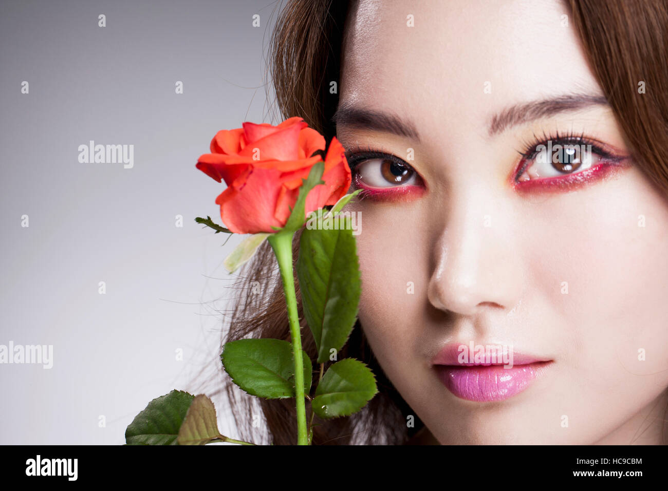 Portrait de jeune femme coréenne en propulsion eye liner posant avec une rose rouge Banque D'Images