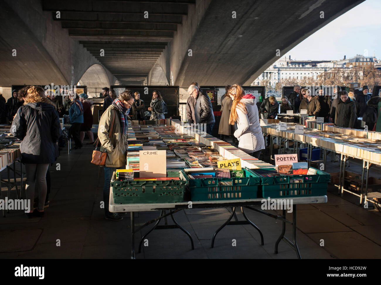 Les gens parcourant sous le pont du marché du livre sur London South Bank par Tamise Banque D'Images