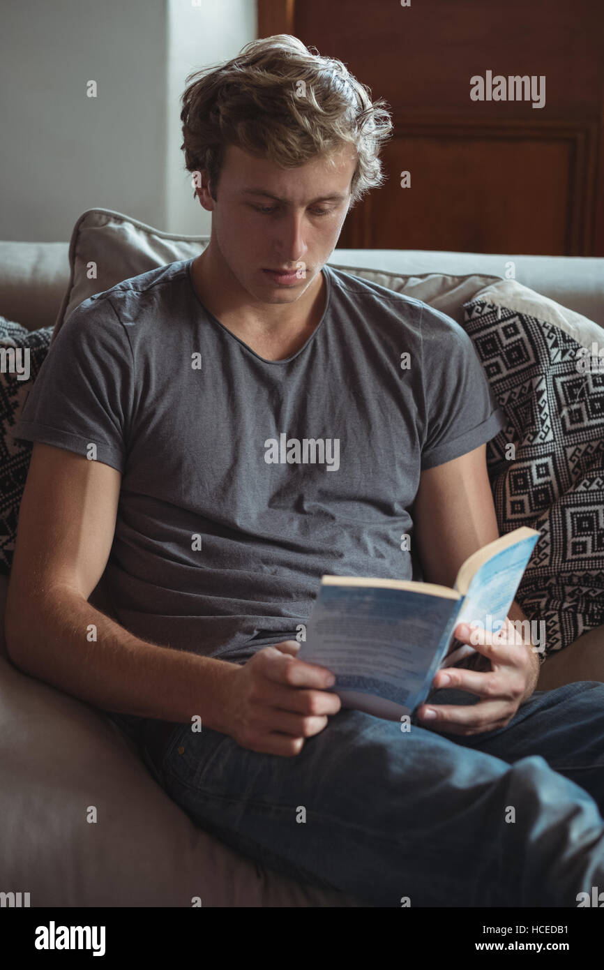 Man sitting on sofa reading a book Banque D'Images