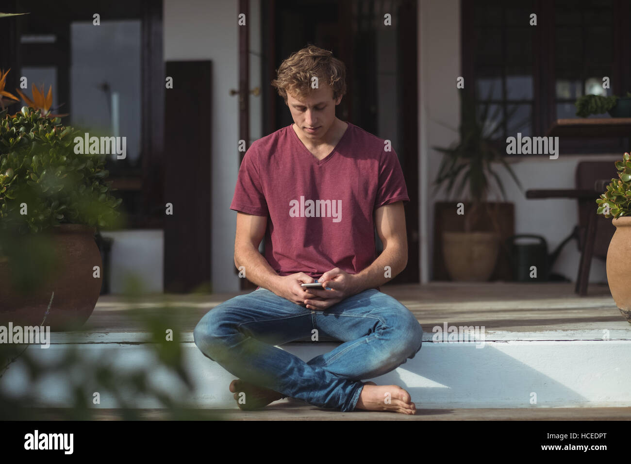 Homme assis sur le porche et l'aide de mobile phone Banque D'Images