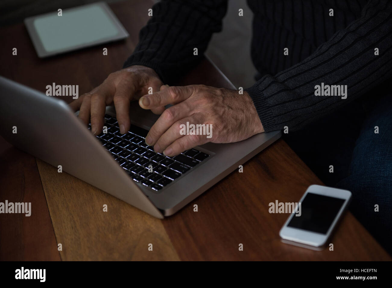 L'homme assis à table et à l'aide d'ordinateur portable à la maison Banque D'Images