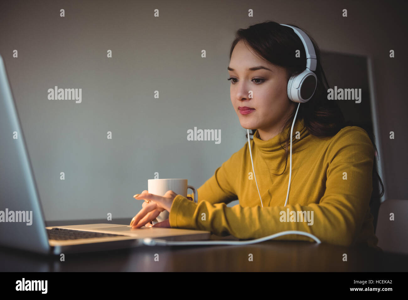 Woman listening to headphones while using laptop Banque D'Images