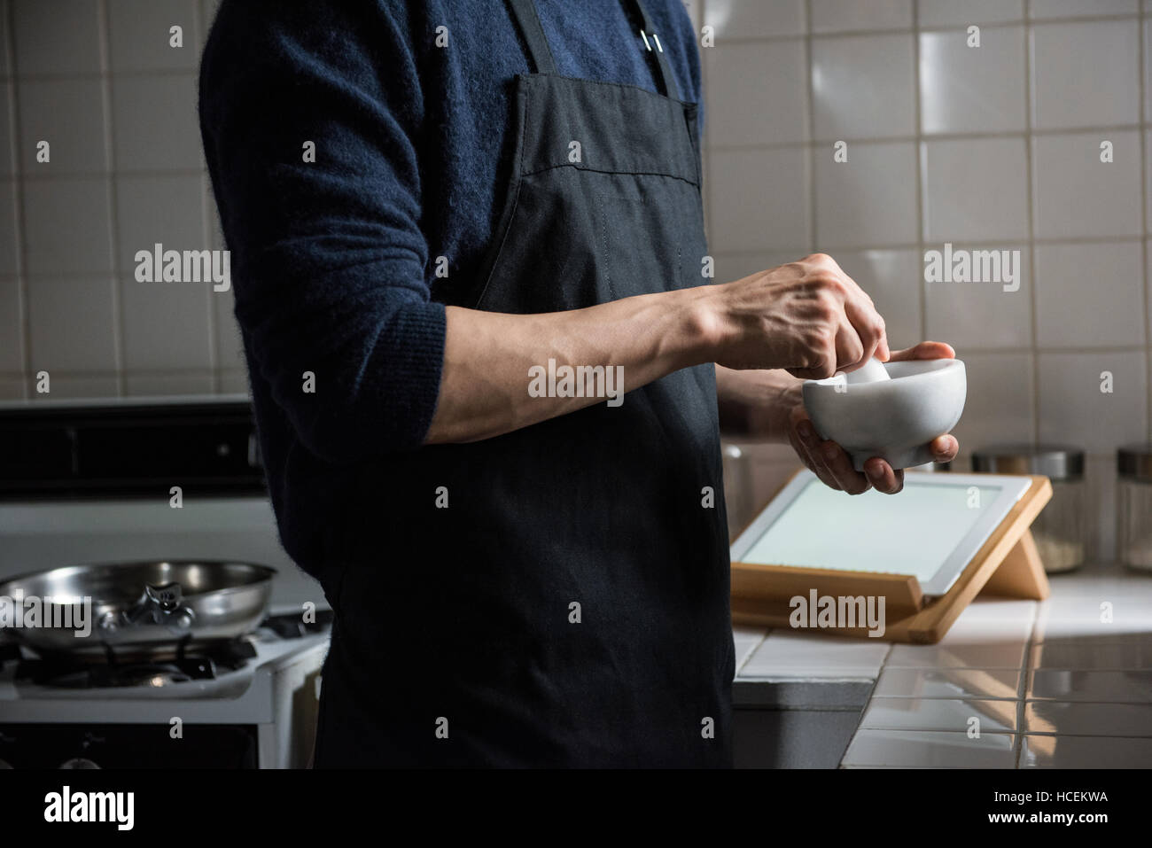 L'homme à l'aide d'un pilon et le mortier dans la cuisine à la maison Banque D'Images