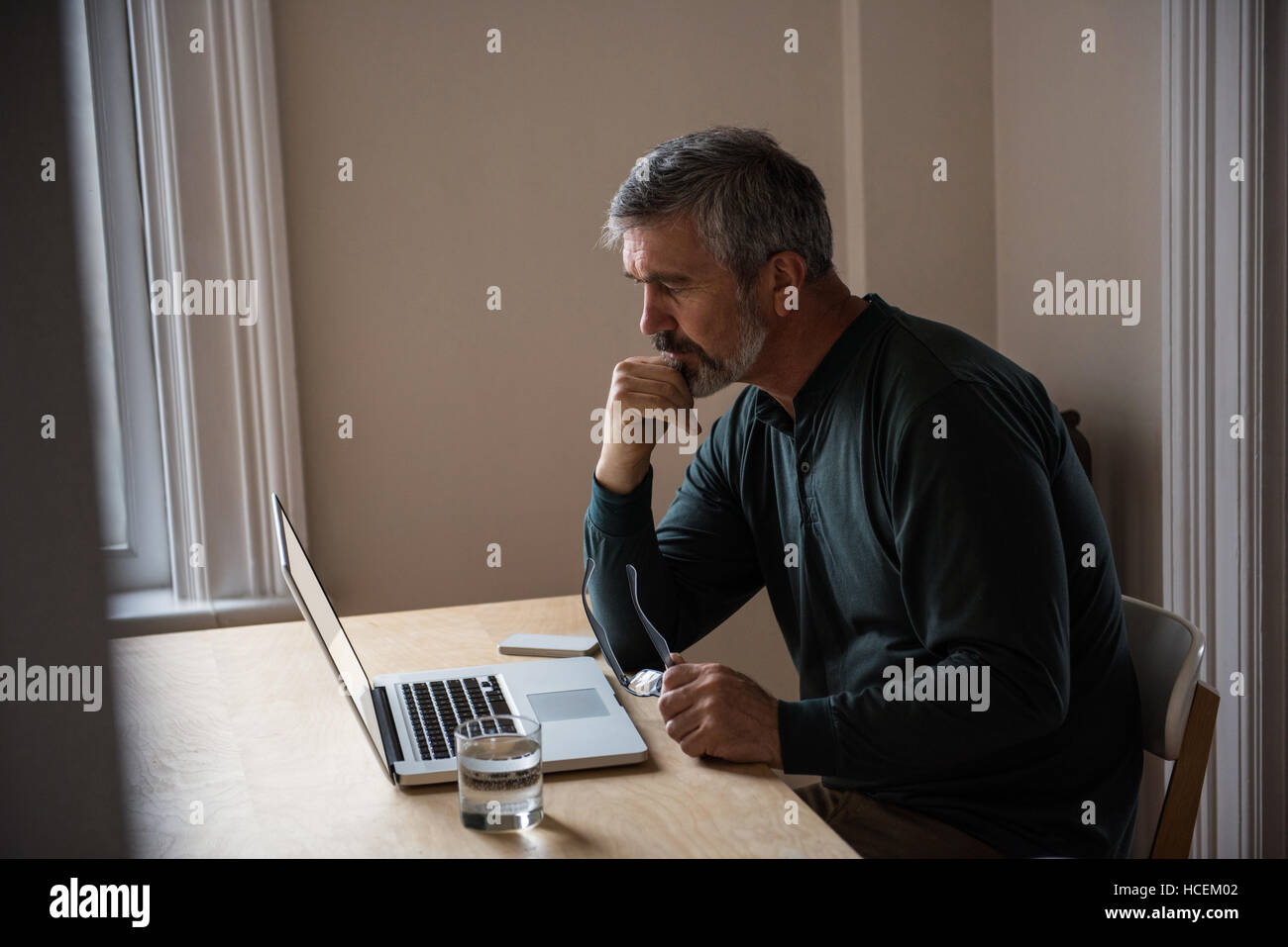 Homme assis avec un ordinateur portable dans la salle de séjour Banque D'Images