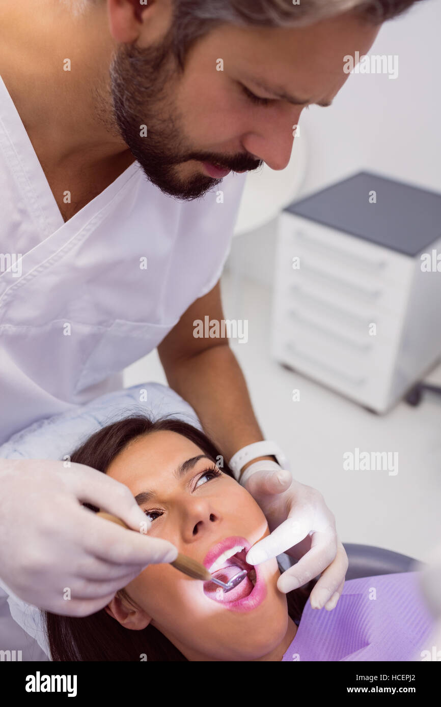 L'examen patient femme dentiste dents avec un miroir de la bouche Banque D'Images