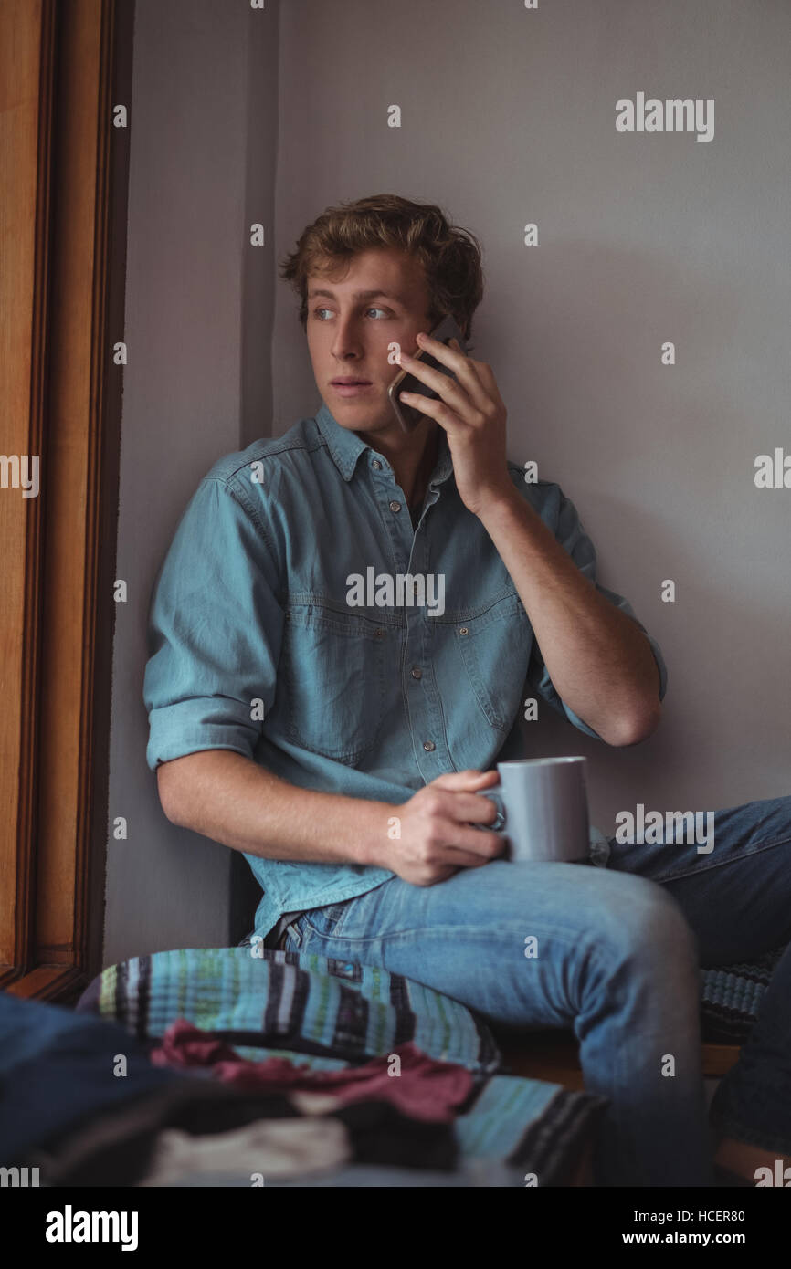 Man holding Coffee cup talking on mobile phone Banque D'Images