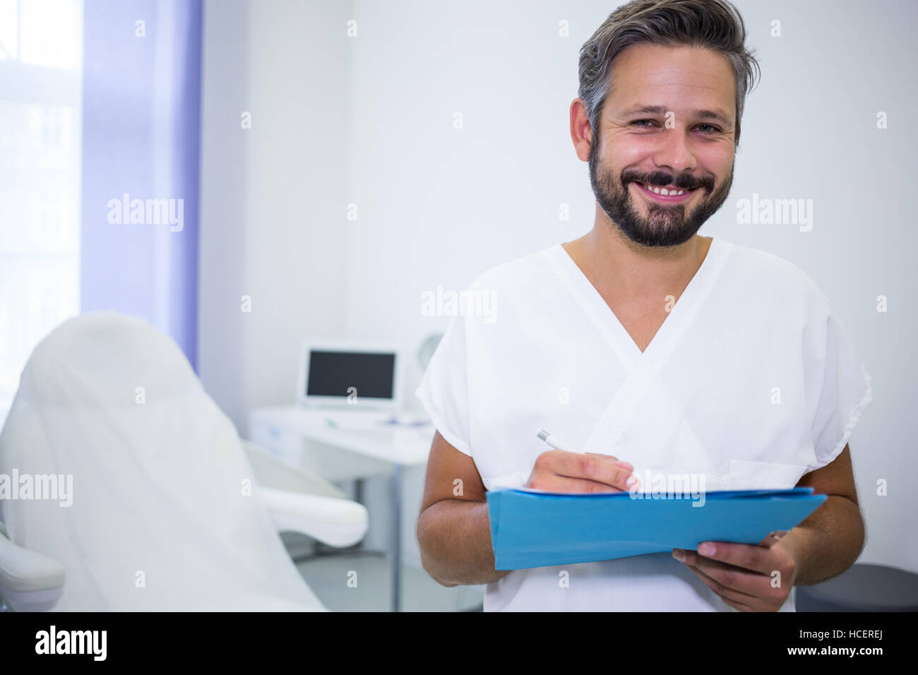 Smiling doctor écrit sur les rapports médicaux en clinique Banque D'Images