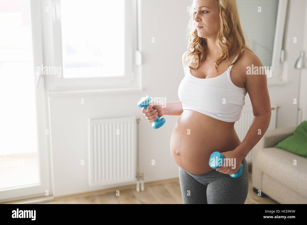 Femme enceinte avec haltères d'entraînement pour rester actif Banque D'Images