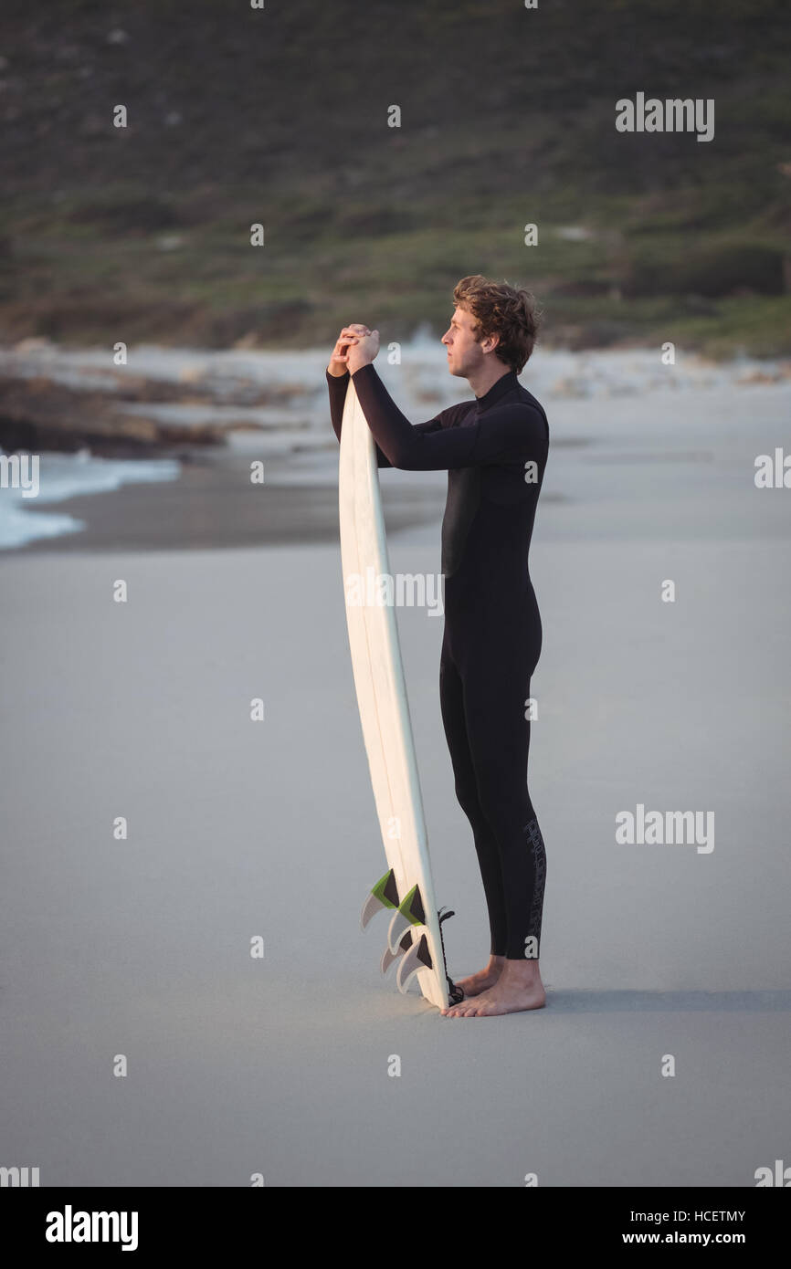 Man wearing wetsuit standing on beach Banque D'Images