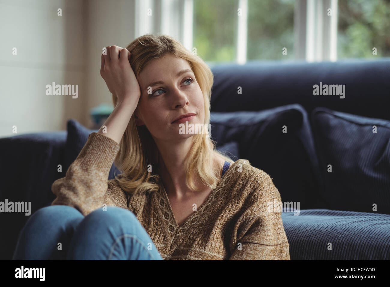 Thoughtful woman sitting in living room Banque D'Images