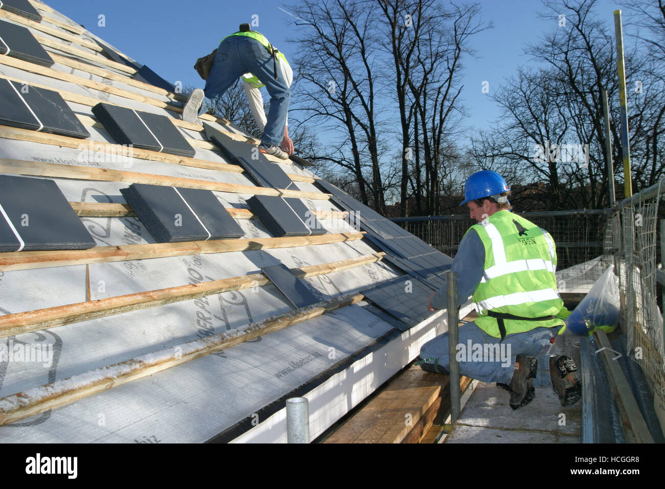 Deux couvreurs fixer le toit de tuiles en ardoise sur un nouveau développement domiciliaire de Richmond, dans le sud de Londres, au Royaume-Uni. Banque D'Images