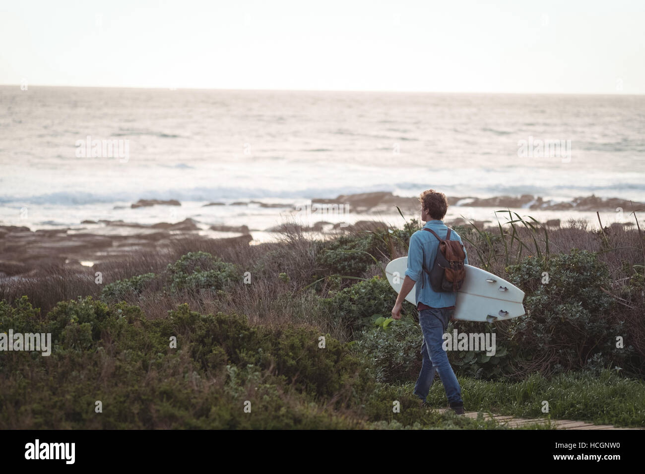 Homme portant un surf randonnée par la mer Banque D'Images