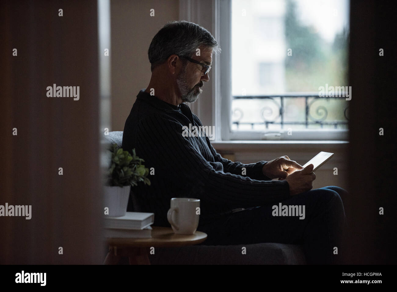 Man using digital tablet in living room Banque D'Images