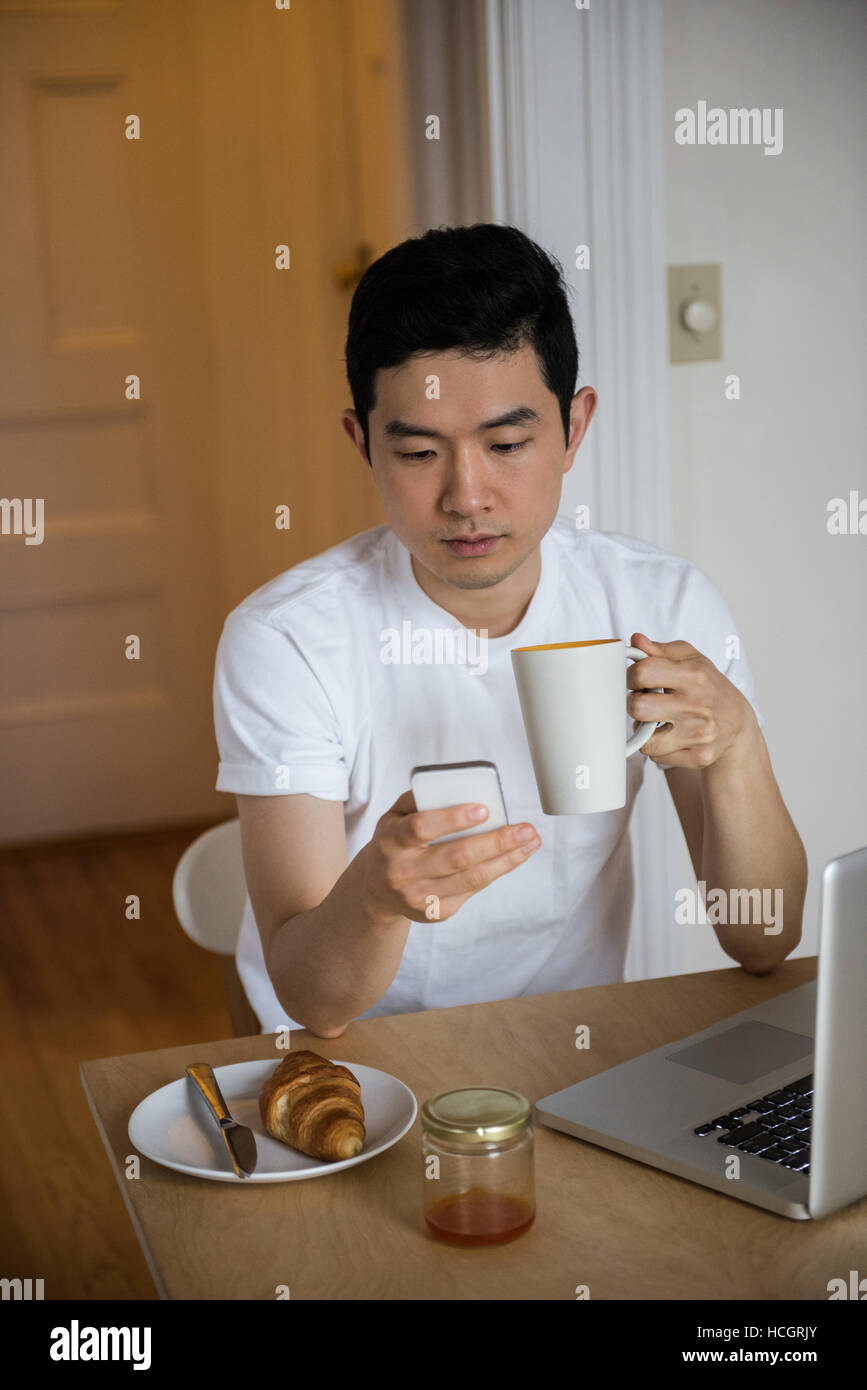 L'homme en utilisant mobilephone tout en ayant une tasse de café Banque D'Images