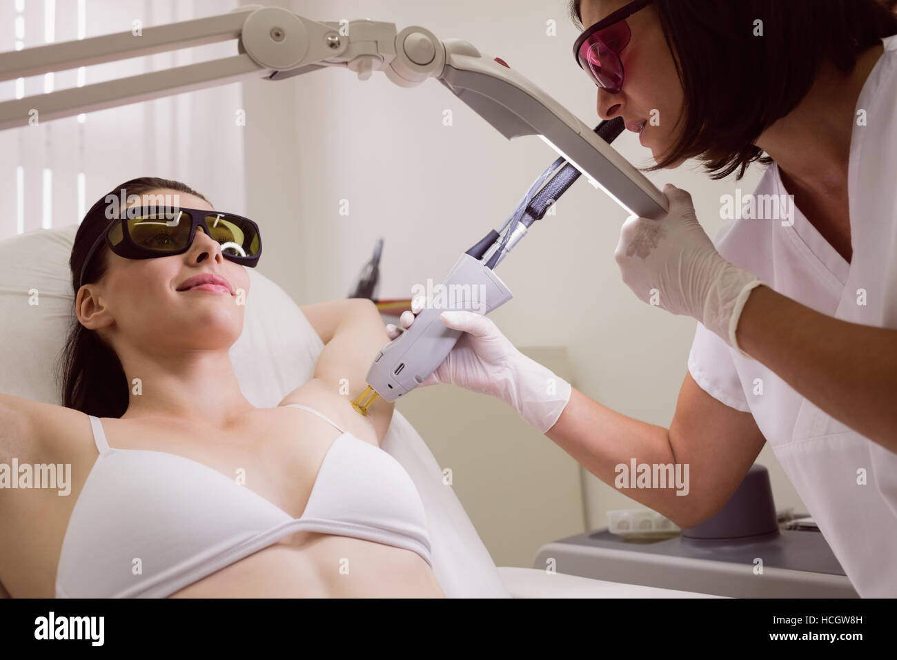 Médecin effectuant l'enlèvement de cheveux de laser sur la peau du patient Banque D'Images
