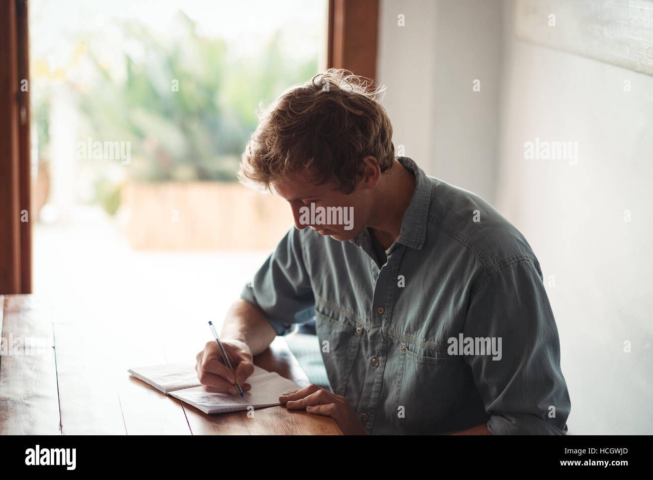 Man sitting at desk writing on notebook Banque D'Images