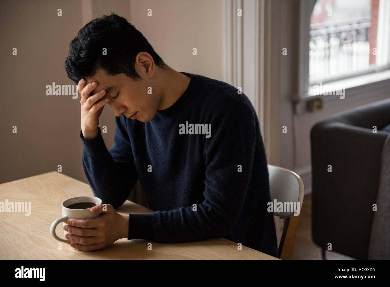 Tendu man sitting at table with coffee cup Banque D'Images