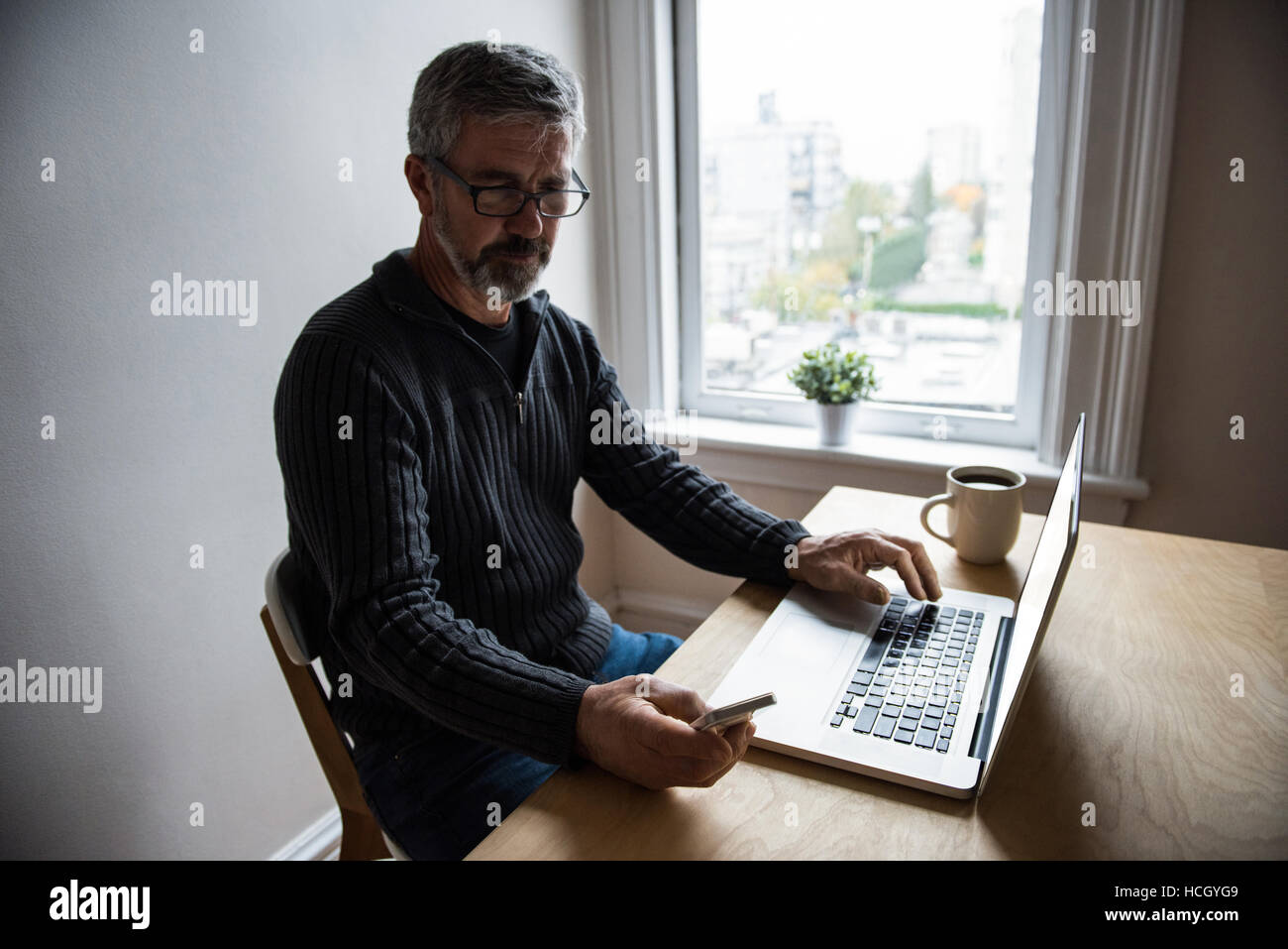 Man using laptop and mobile phone at home Banque D'Images