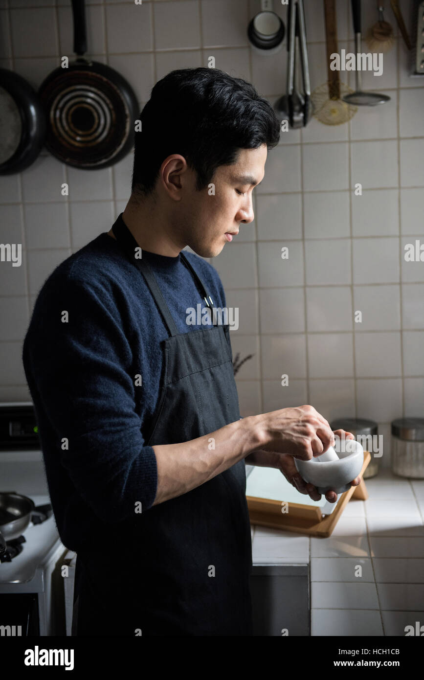 L'homme à l'aide d'un pilon et le mortier dans la cuisine Banque D'Images