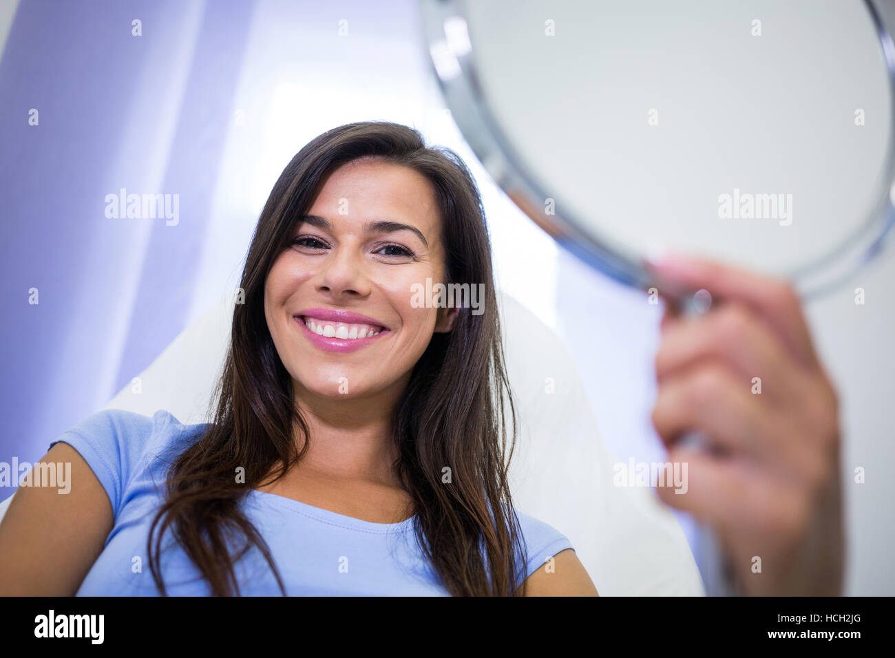 Smiling patient tenant un miroir à la clinique Banque D'Images