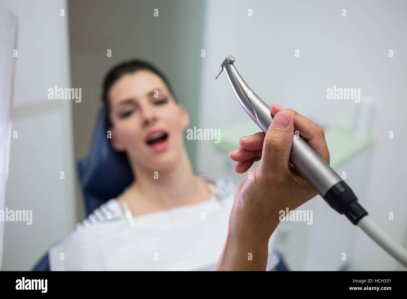 Close-up de dentiste tenant une pièce à main dentaire dentisterie, tout en examinant une femme Banque D'Images