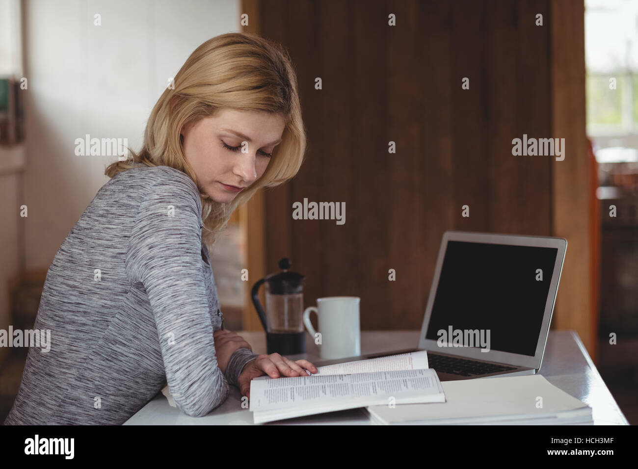 Belle femme assise à table et reading book Banque D'Images