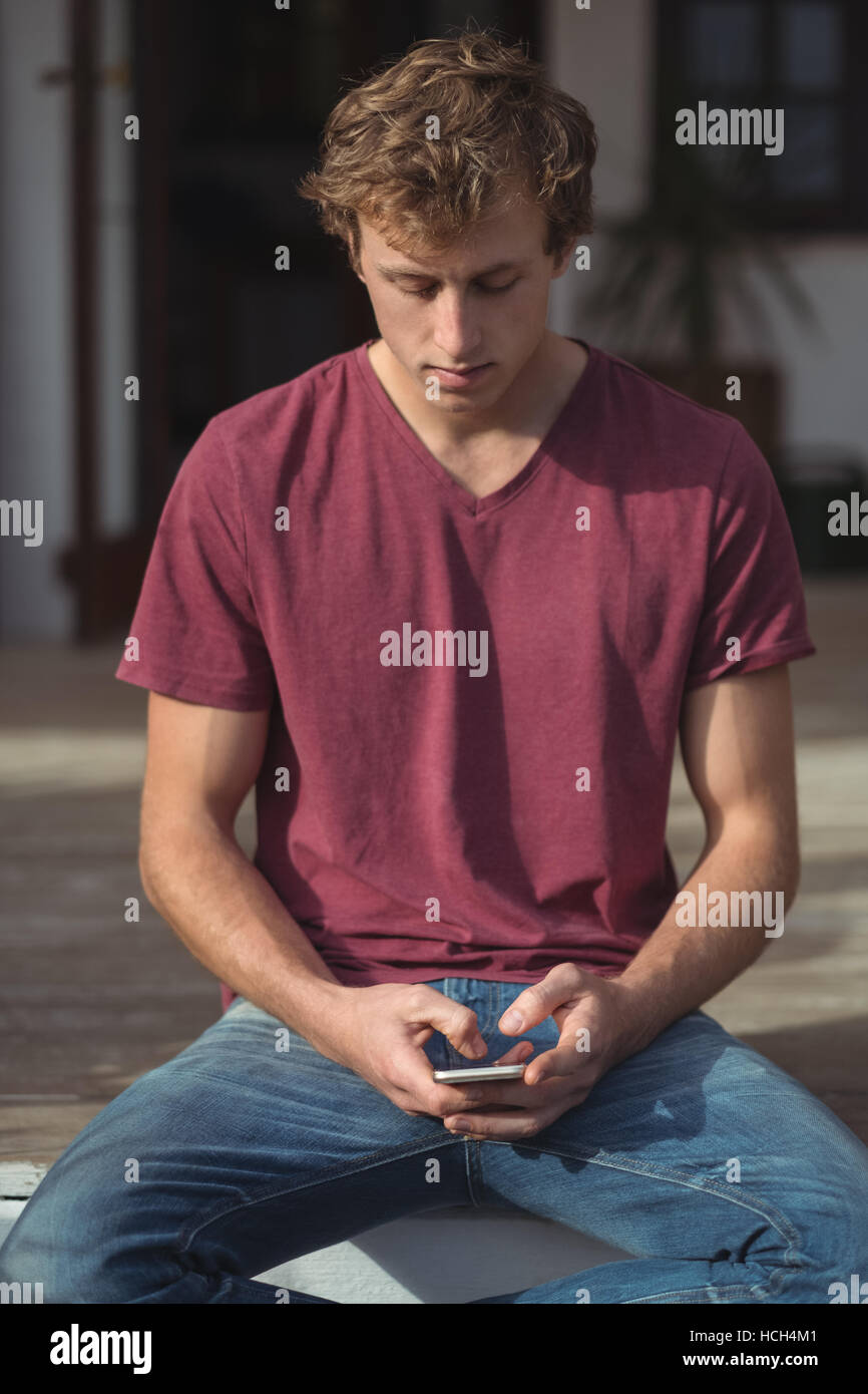 Homme assis sur le porche et l'aide de mobile phone Banque D'Images