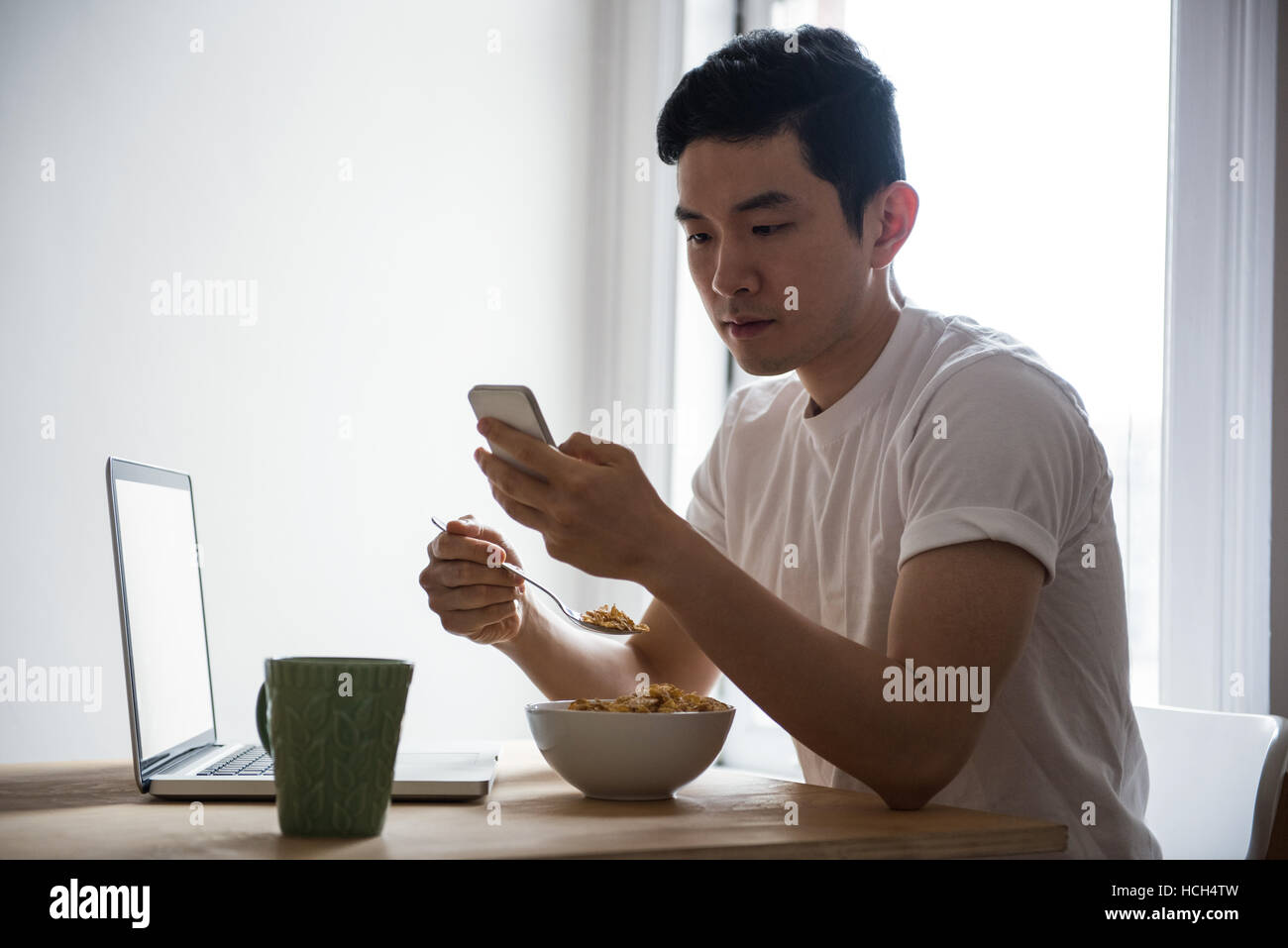 L'homme à l'aide de téléphone mobile pendant le petit-déjeuner Banque D'Images