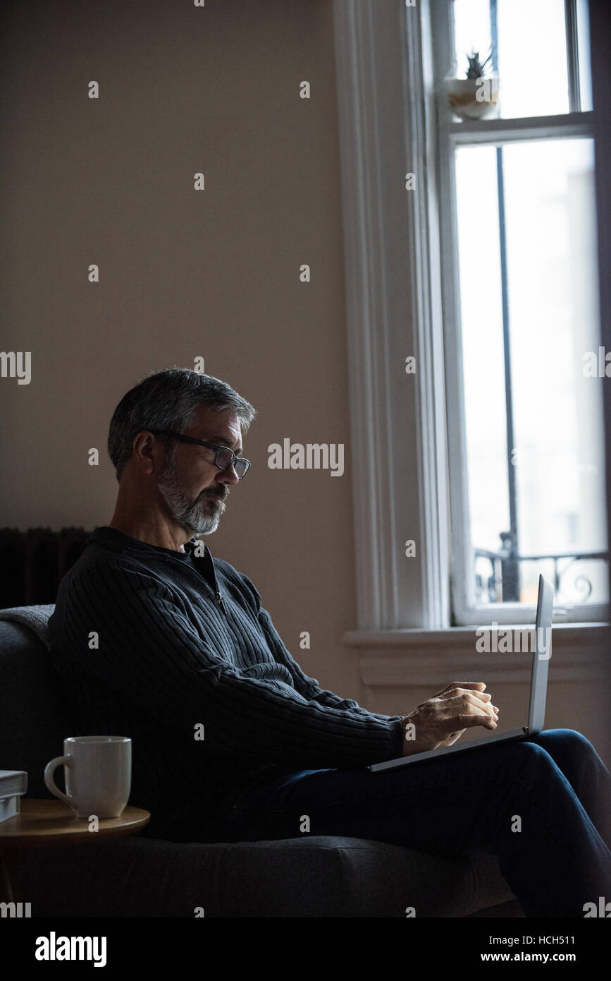Man sitting on sofa and using laptop Banque D'Images