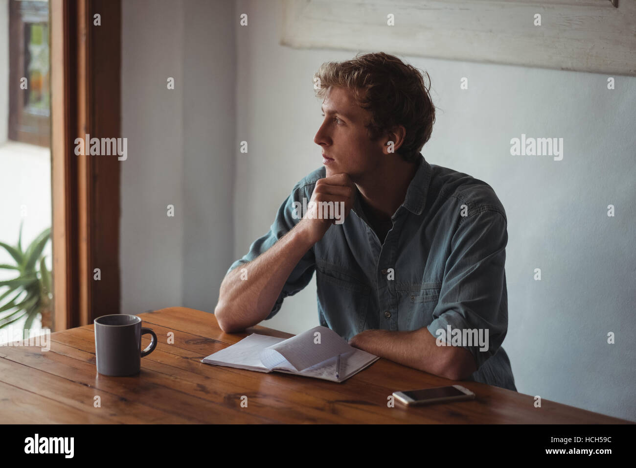 Thoughtful man sitting bureau avec ordinateur portable Banque D'Images