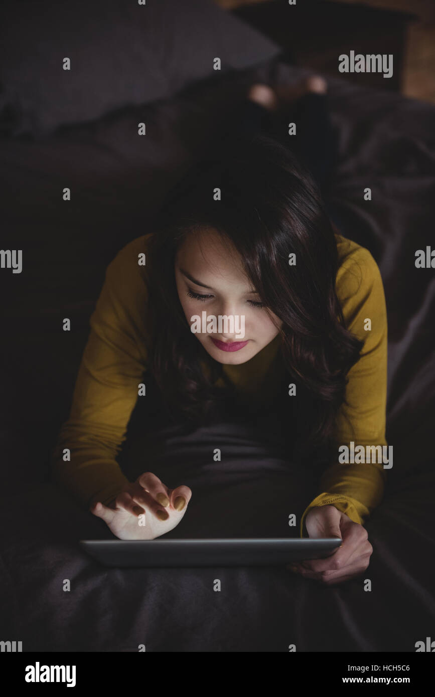 Woman using digital tablet in bedroom Banque D'Images