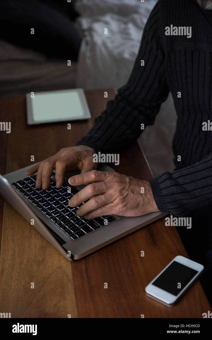 L'homme assis à table et à l'aide d'ordinateur portable à la maison Banque D'Images
