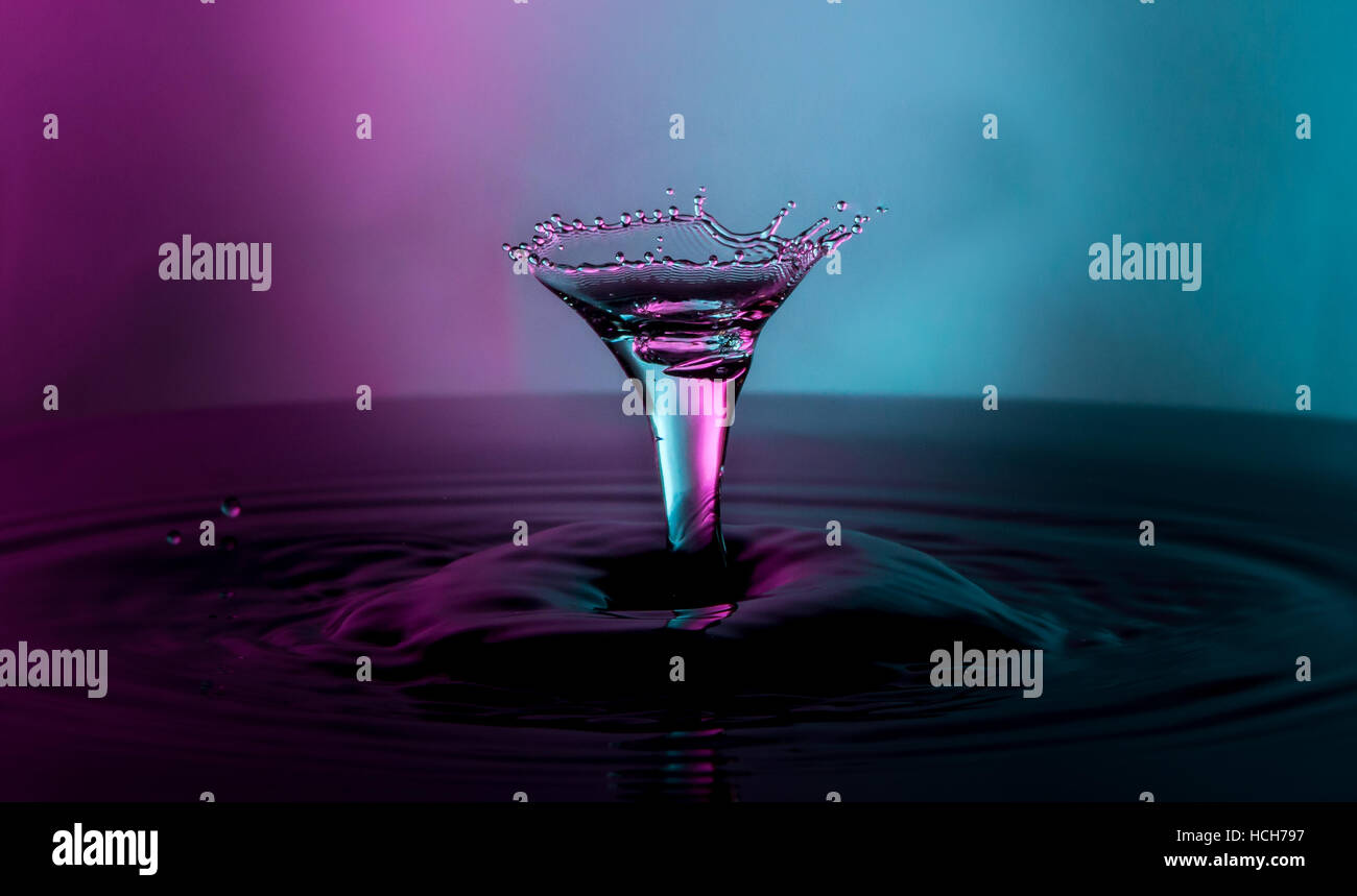 Capture de goutte d'eau en forme de verre à cocktail avec de la lumière bleue et violette Banque D'Images