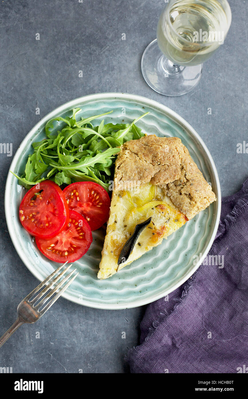 Galette de pommes de terre Gruyère Sauge servi avec des tomates, roquette et le vin blanc. Photographié sur un fond gris en vue de dessus. Banque D'Images