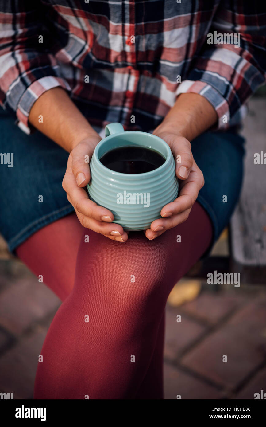 Une femme tenant une tasse de thé dans le parc. Banque D'Images