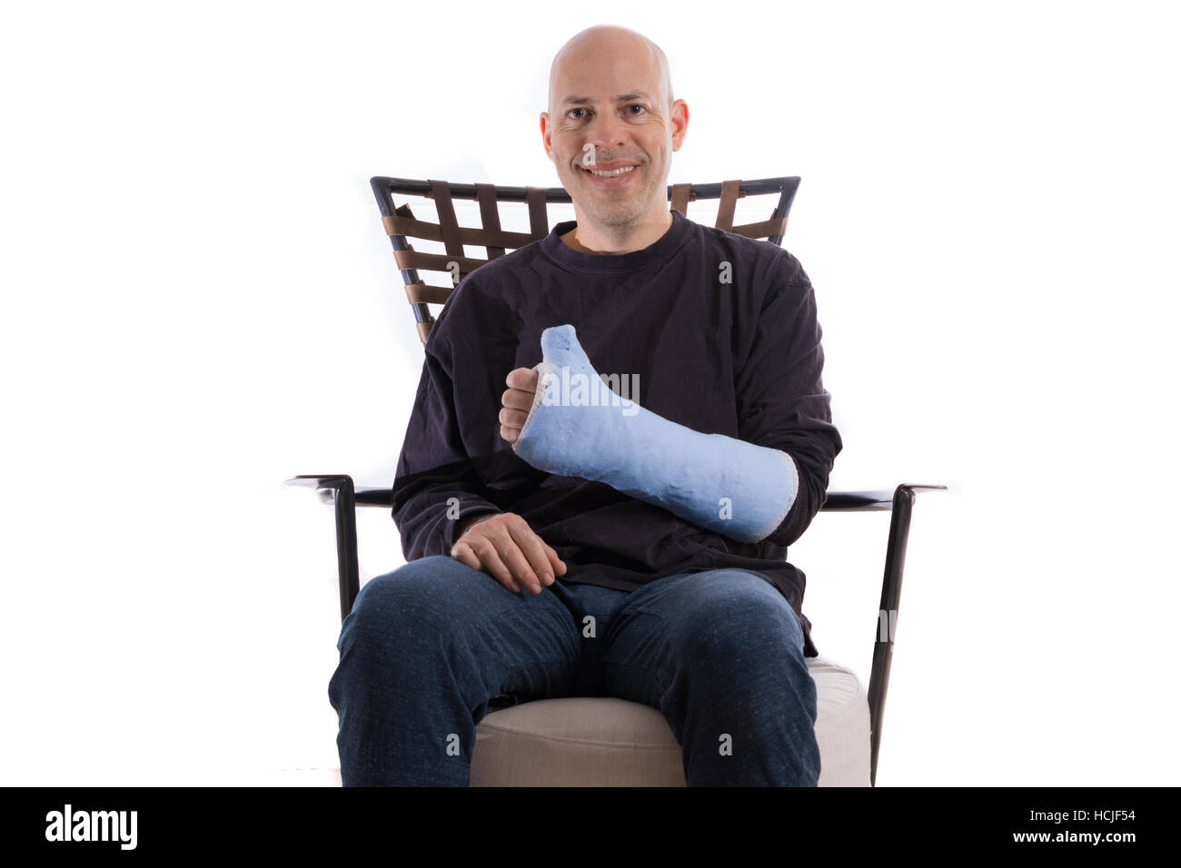 Heureux jeune homme assis sur un canapé faisant un Thumbs up sign avec son bras en fonte Banque D'Images