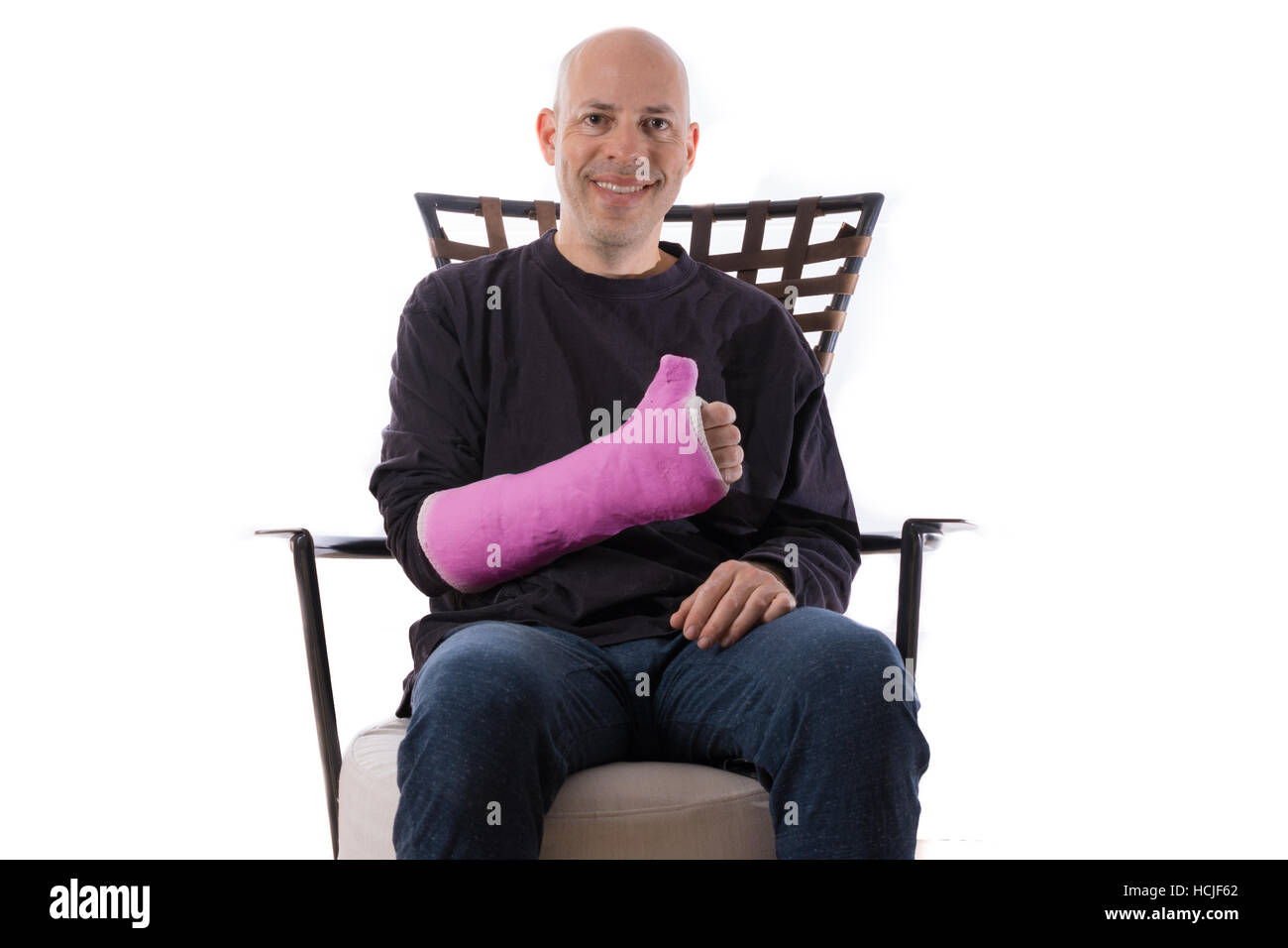 Heureux jeune homme assis sur un canapé faisant un Thumbs up sign avec son bras en fonte Banque D'Images