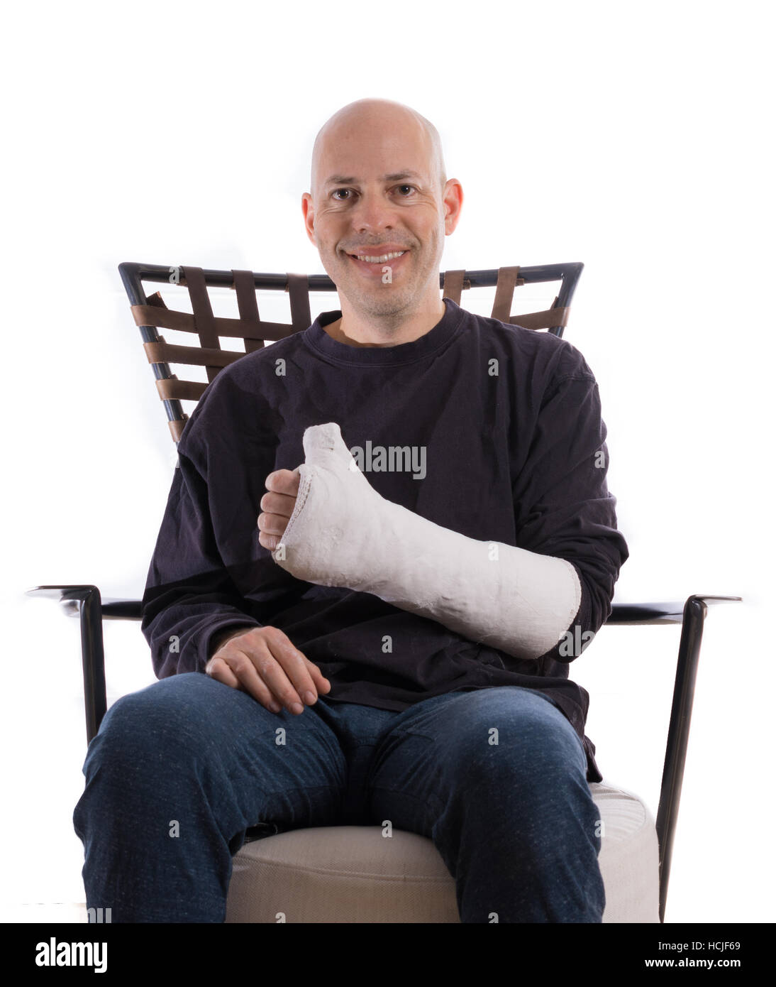 Heureux jeune homme assis sur un canapé faisant un Thumbs up sign avec son bras en fonte Banque D'Images