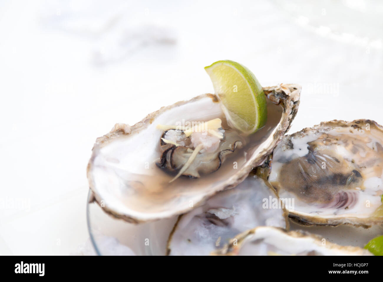 Les coquilles des huîtres a ouvert partiellement cuits servis sur plaque de verre avec le gingembre et un morceau de citron sur le côté, Santa Catarina, Brésil Banque D'Images