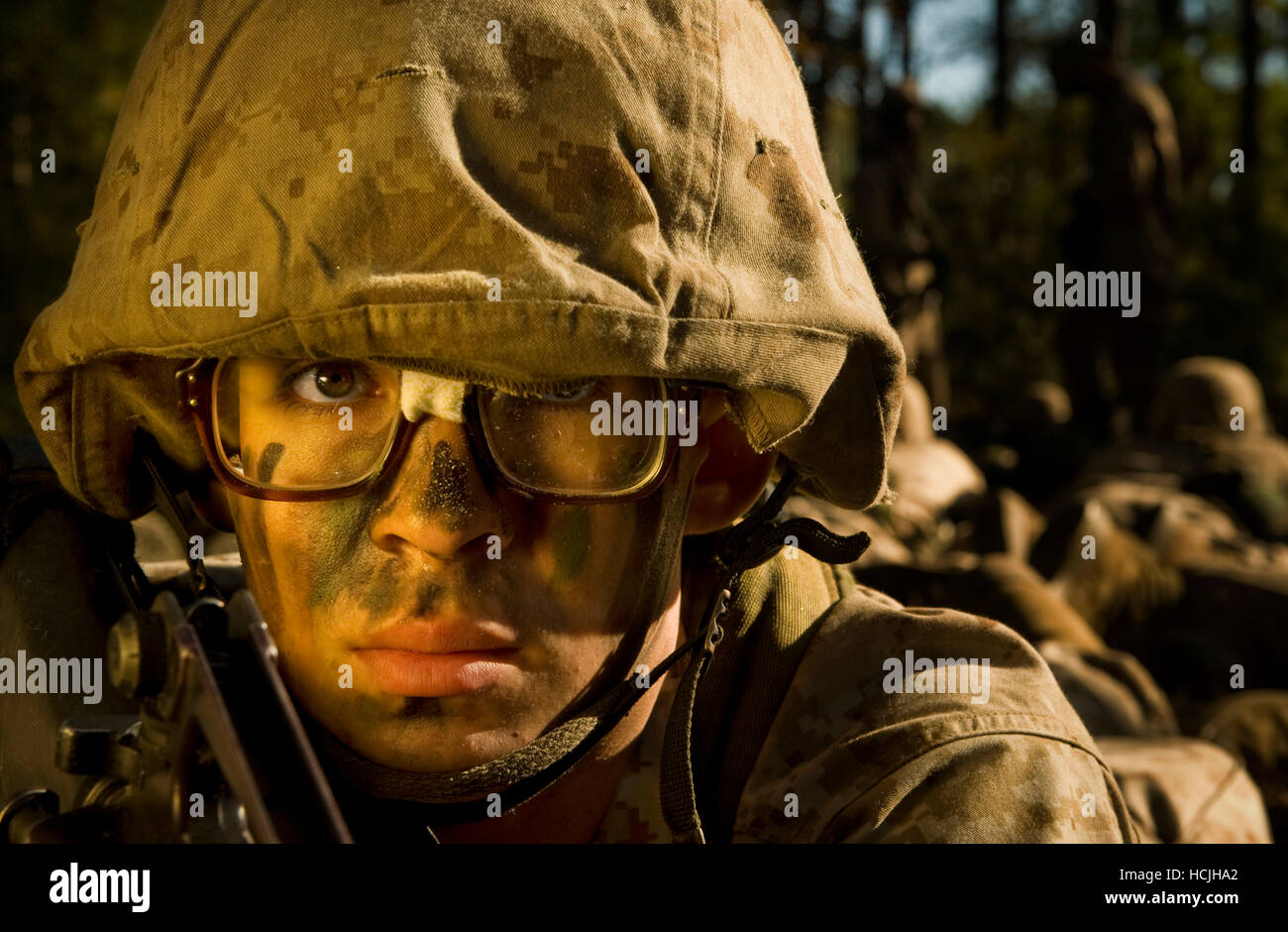Une aire marine de recruter a maintenant l'ensemble de bandes son émis sur le terrain lors d'un lunettes exercice d'entraînement. Il porte un uniforme de camouflage de désert et un casque. Banque D'Images
