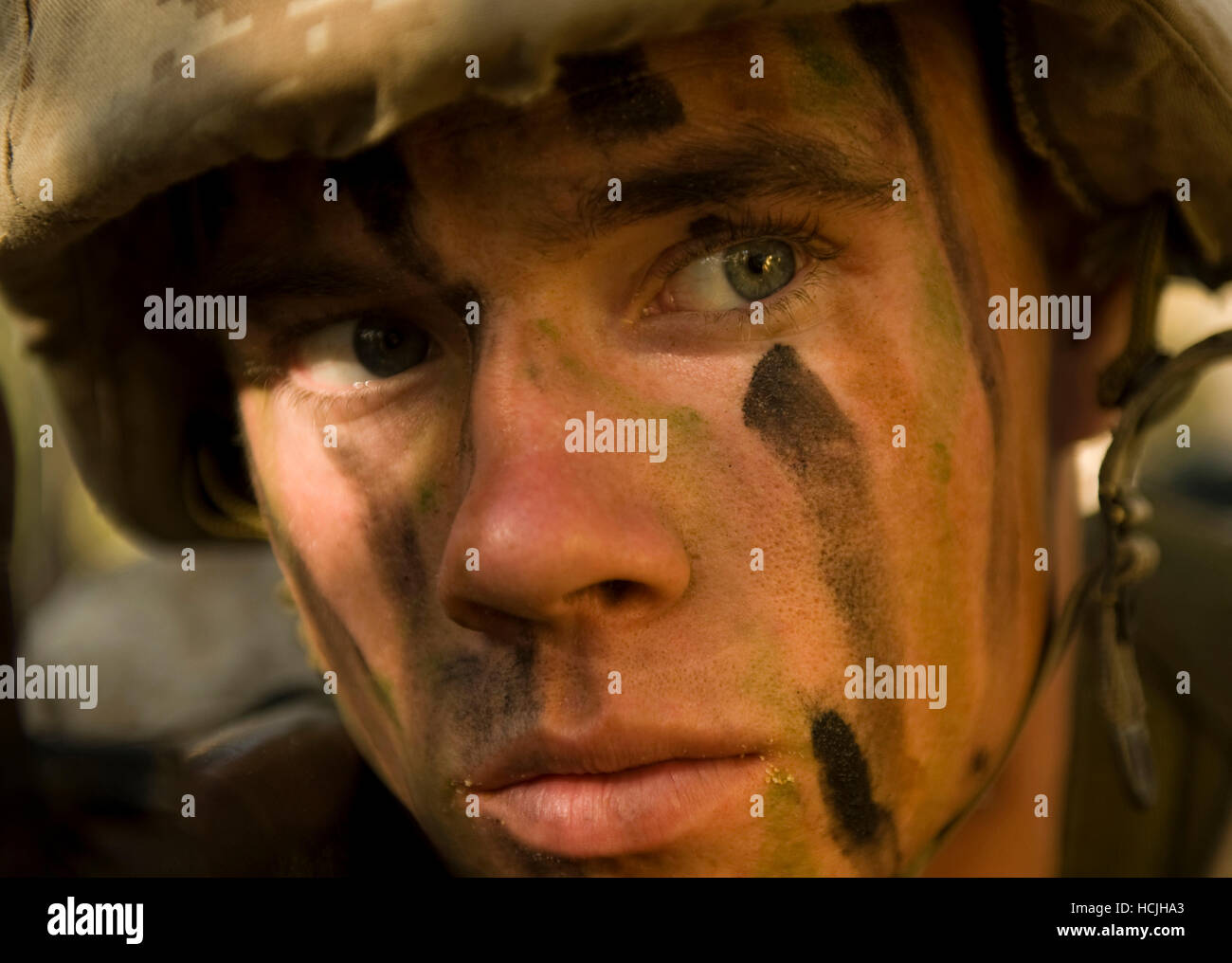 Une aire marine de recruter fournit la sécurité sur le terrain lors d'un exercice d'entraînement. Il porte un uniforme de camouflage de désert et un casque. Banque D'Images