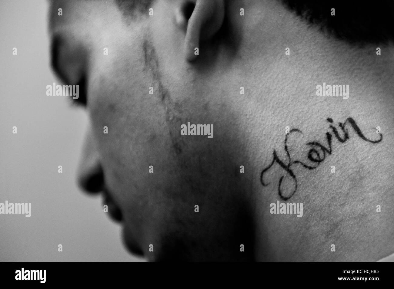 Un homme avec le nom Kevin tatoué sur son cou regarde son sens tout en parlant de la façon dont il a obtenu l'écart des gangs. Banque D'Images
