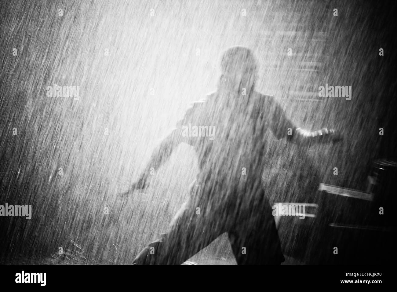 Silhouette d'un homme fuyant sous la pluie dans la nuit. Banque D'Images