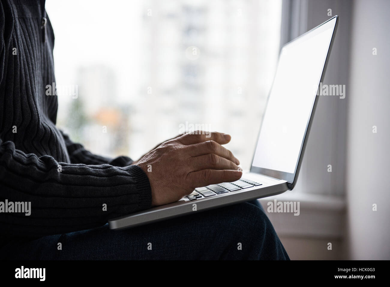 Man sitting on bed and using laptop at home Banque D'Images