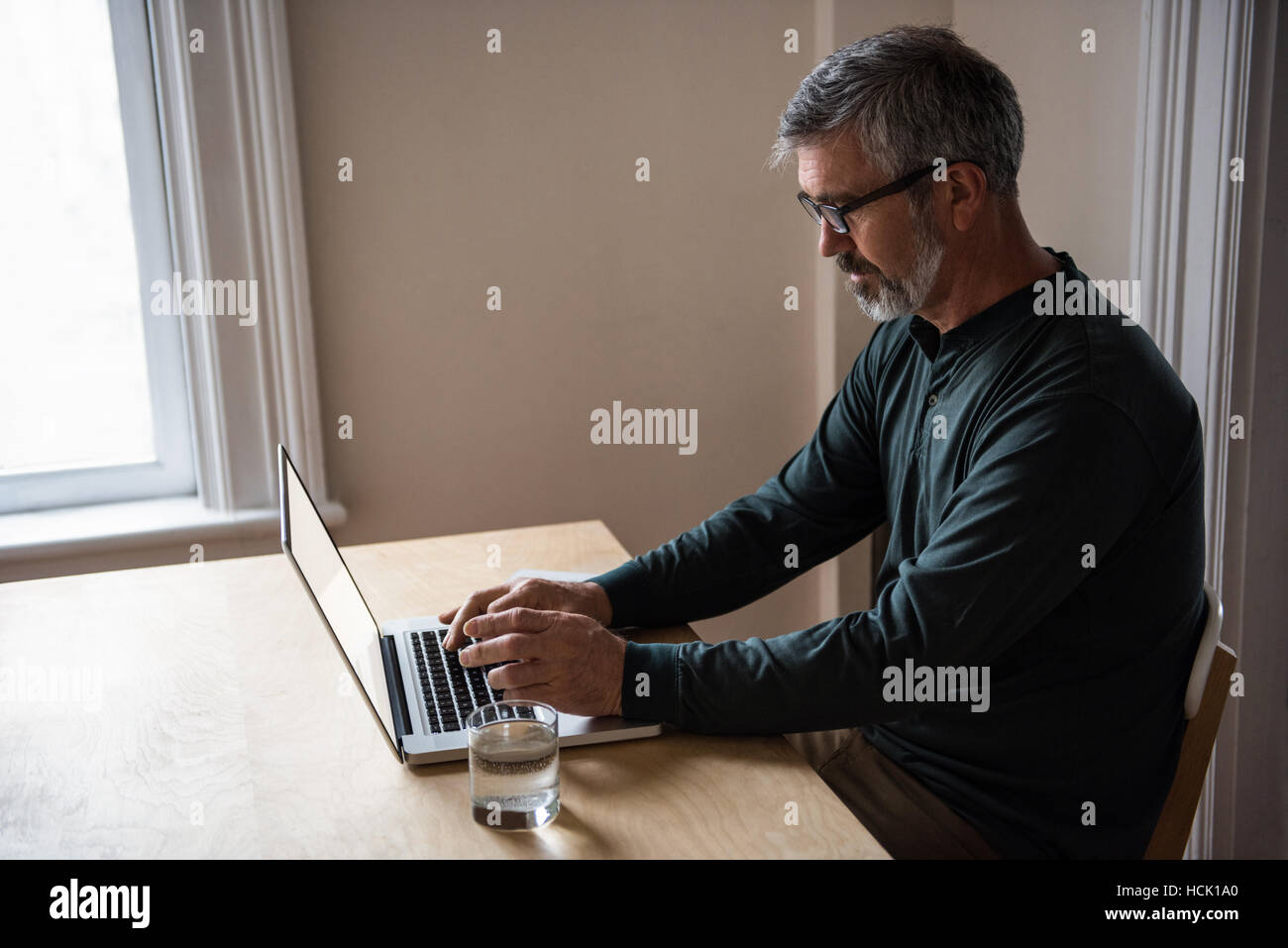 L'homme assis à table et using laptop Banque D'Images