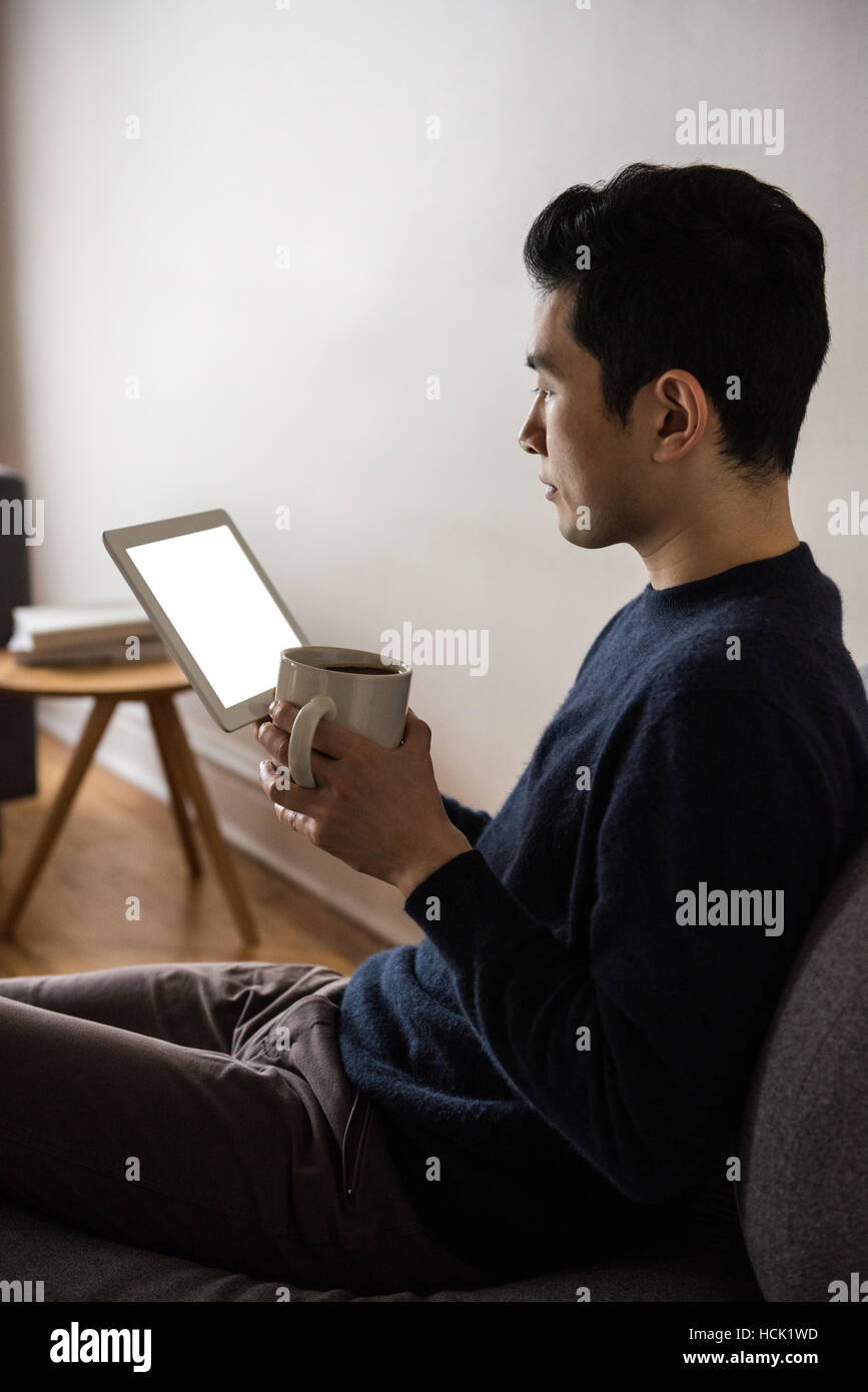 Man using digital tablet while having coffee Banque D'Images