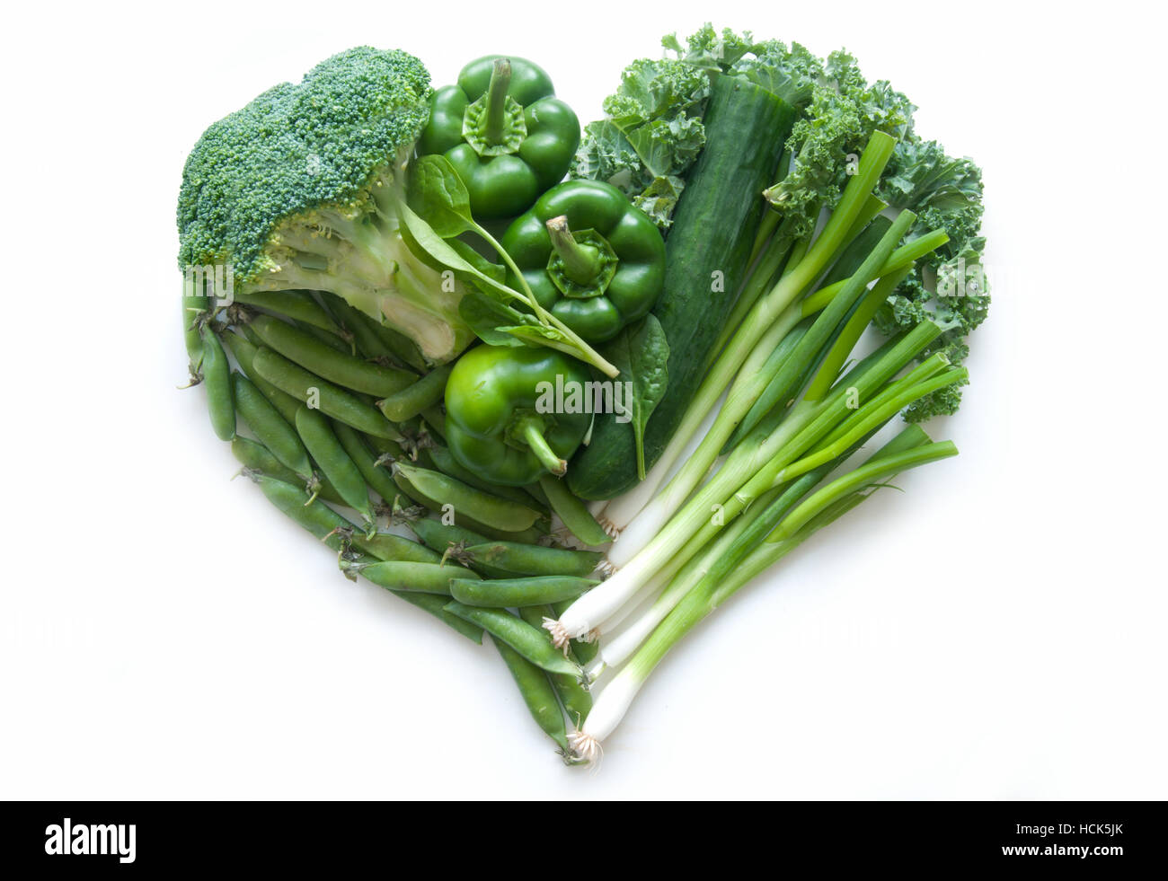 Sélection de légumes verts et de feuilles dont kale et le brocoli en forme de cœur sur un fond blanc Banque D'Images