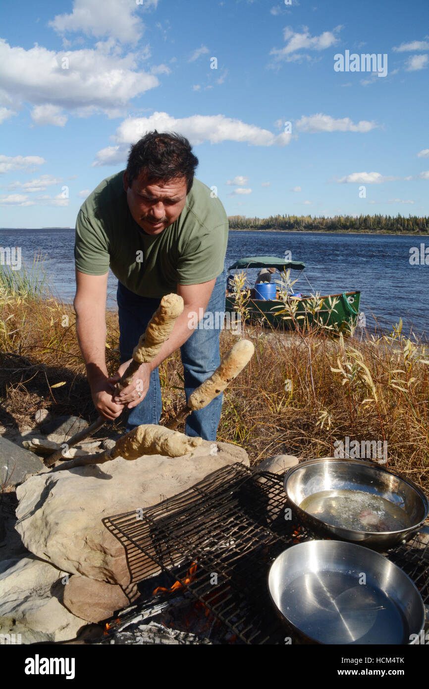 Un indigène de faire du pain bannock sur un bâton, un marché nord-américain des aliments similaires à pain, dans le Nord de l'Ontario, Canada. Banque D'Images