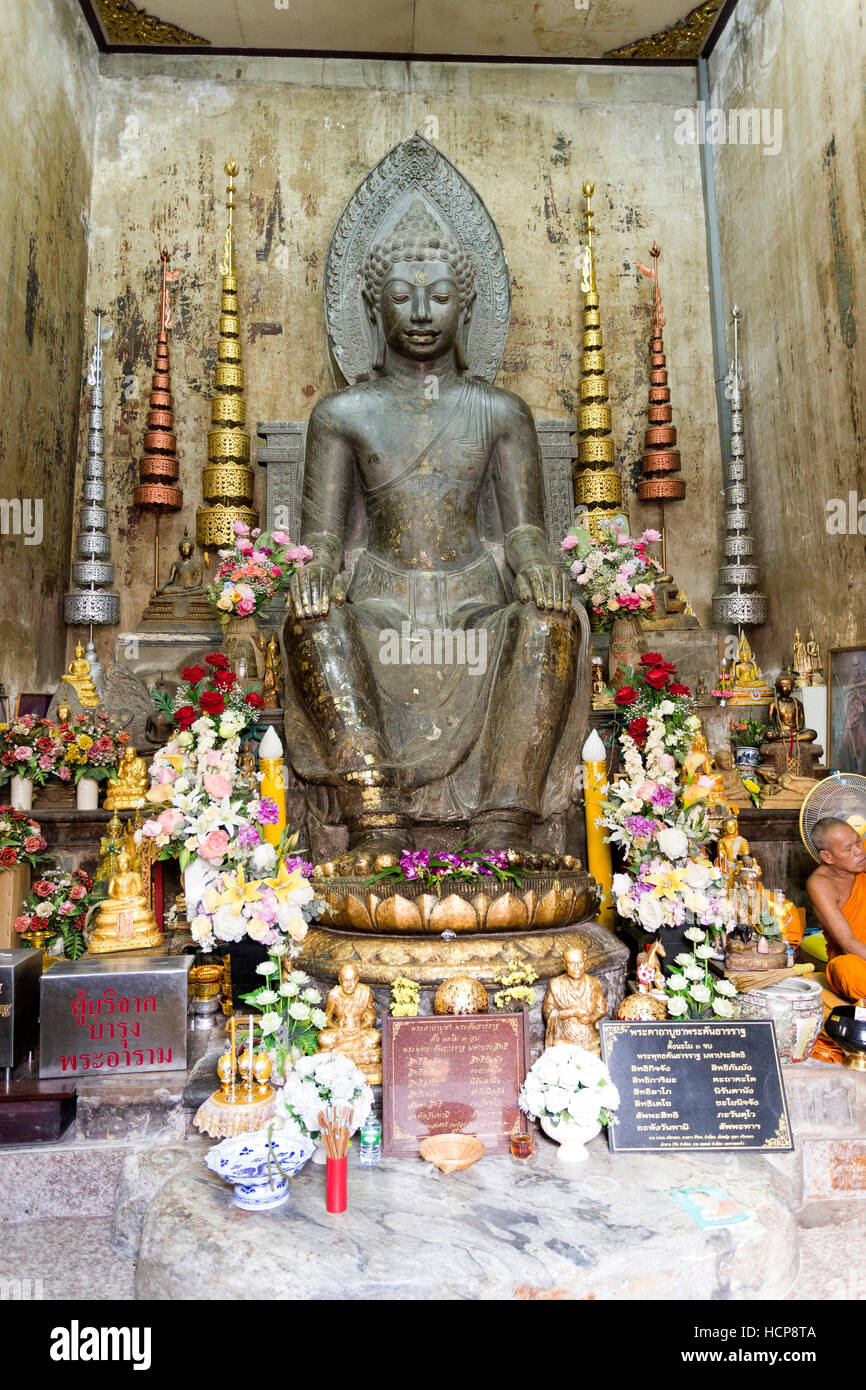 Statue d'un bouddha sculpté dans la pierre noire dans la posture européenne , assis sur une chaise, les mains sur les genoux et les deux pieds sur le sol, dans Ayuttha Banque D'Images